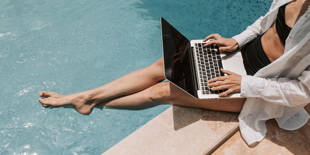 woman with laptop by a pool